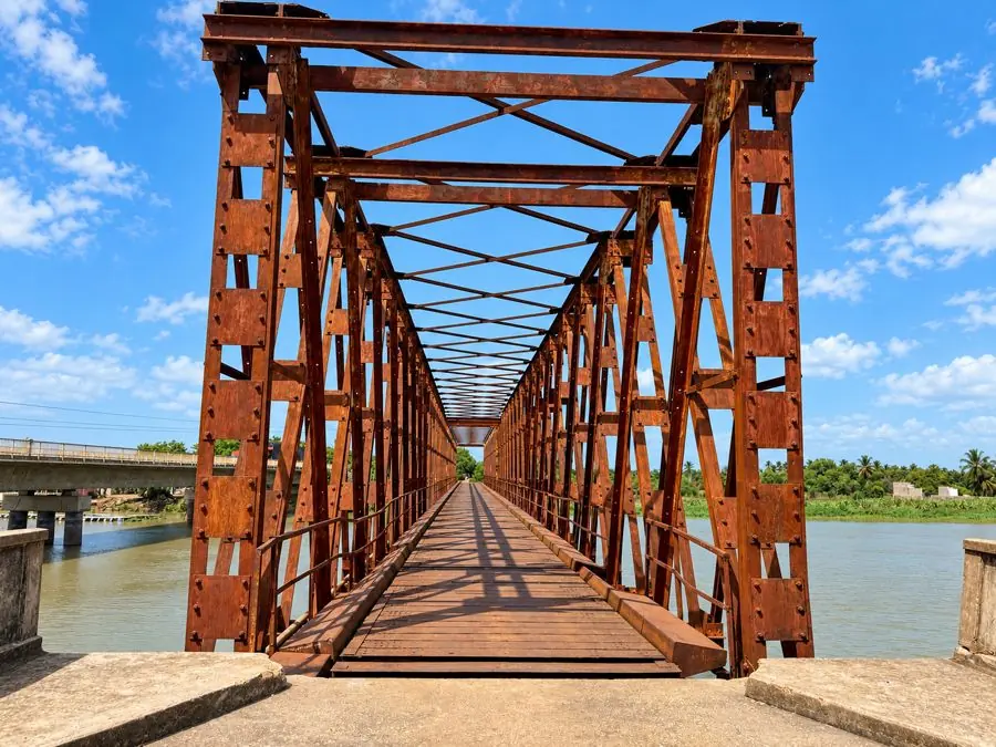 Ancien pont métallique couleur rouille enjambant un fleuve à Grand-Popo au Bénin.