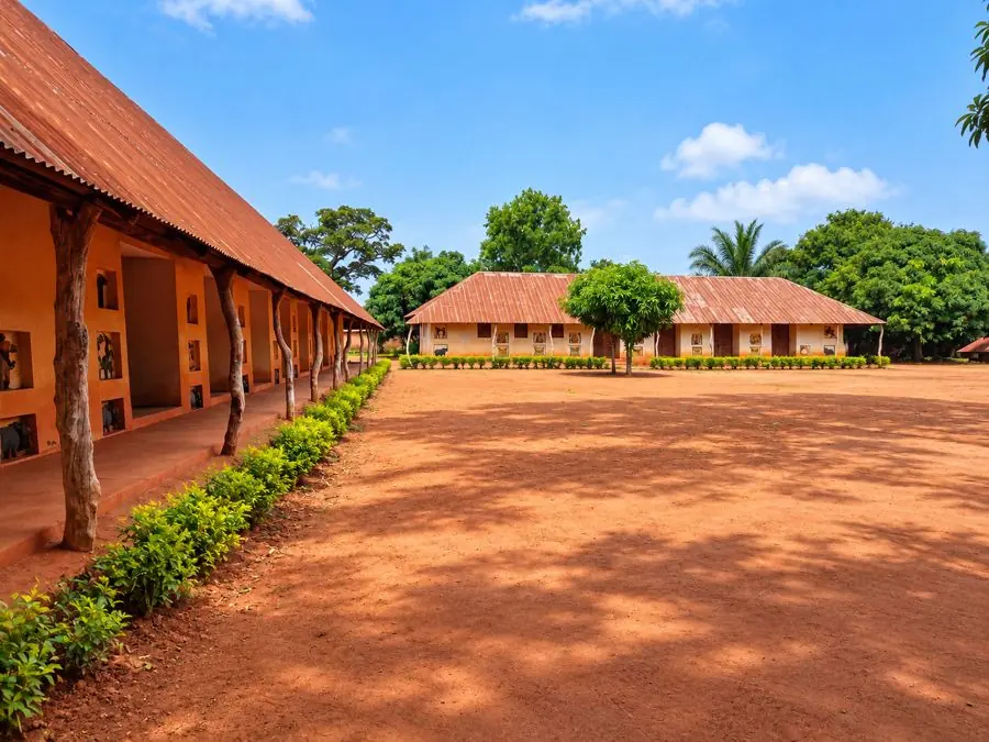 Cour en terre rouge bordée de bâtiments ornés de bas-reliefs à Abomey au Bénin.