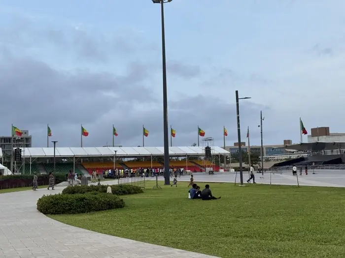 Esplanade aux drapeaux du Bénin, avec des promeneurs sur la pelouse.