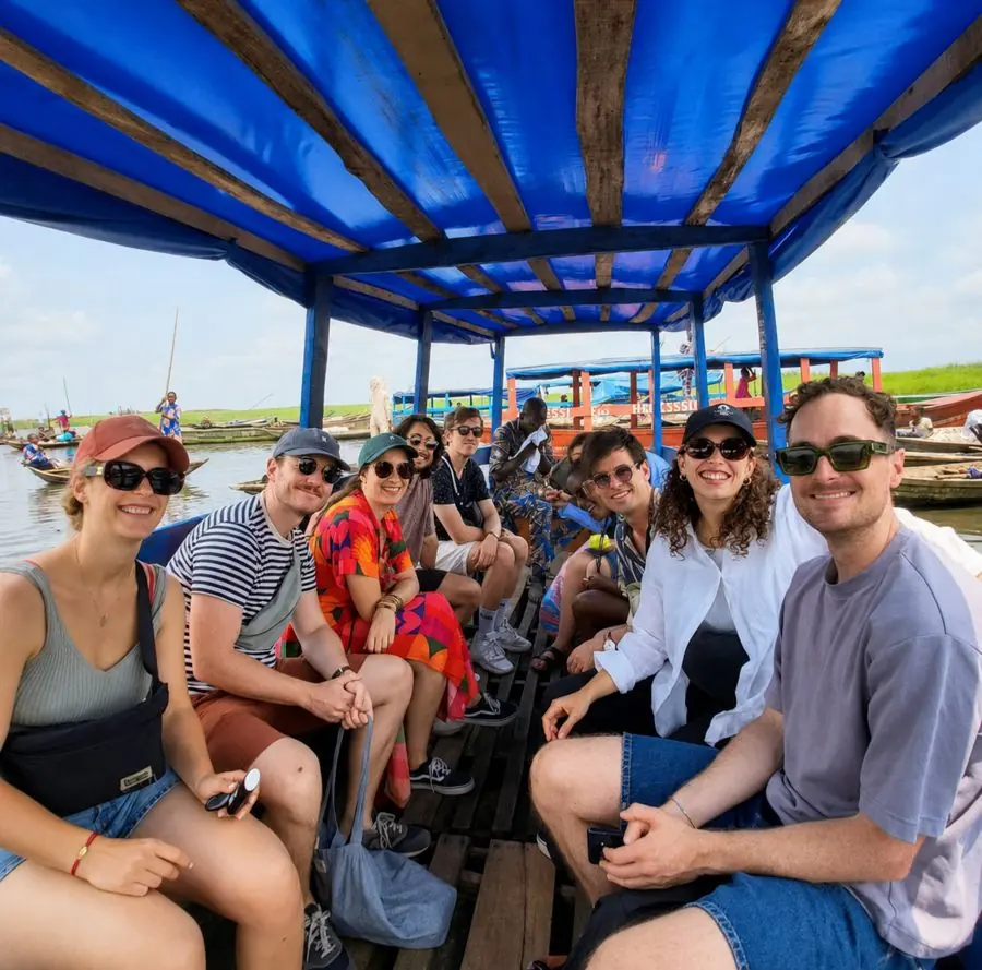 Groupe de visiteurs souriants à bord d’une pirogue couverte lors d’une excursion à Ganvié.