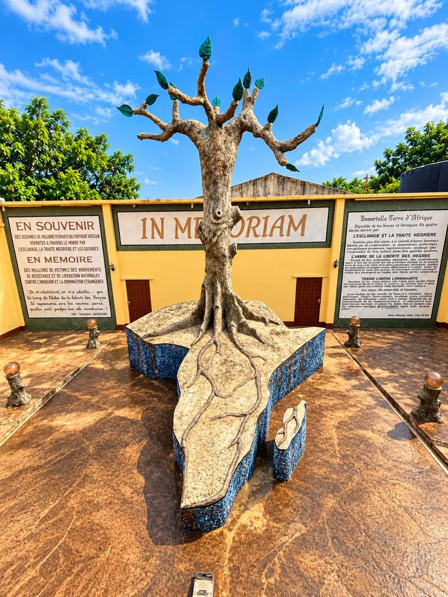 Monument en forme d’arbre devant un mur « In Memoriam » dédié à la mémoire de l’esclavage, à Porto-Novo.