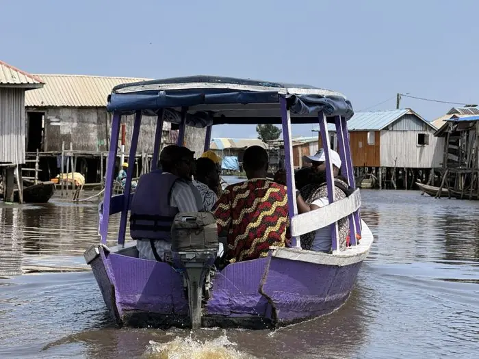 Pirogue motorisée couverte transportant des visiteurs entre les maisons sur pilotis de Ganvié.