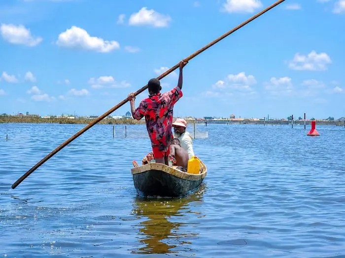 Piroguier debout poussant sa pirogue à la perche sur le lac Nokoué à Ganvié.