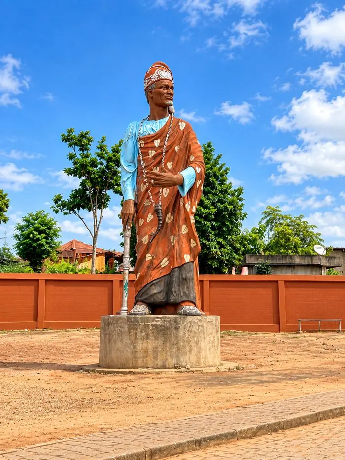 Statue d’un dignitaire en tenue traditionnelle, sur un socle, à Porto-Novo.