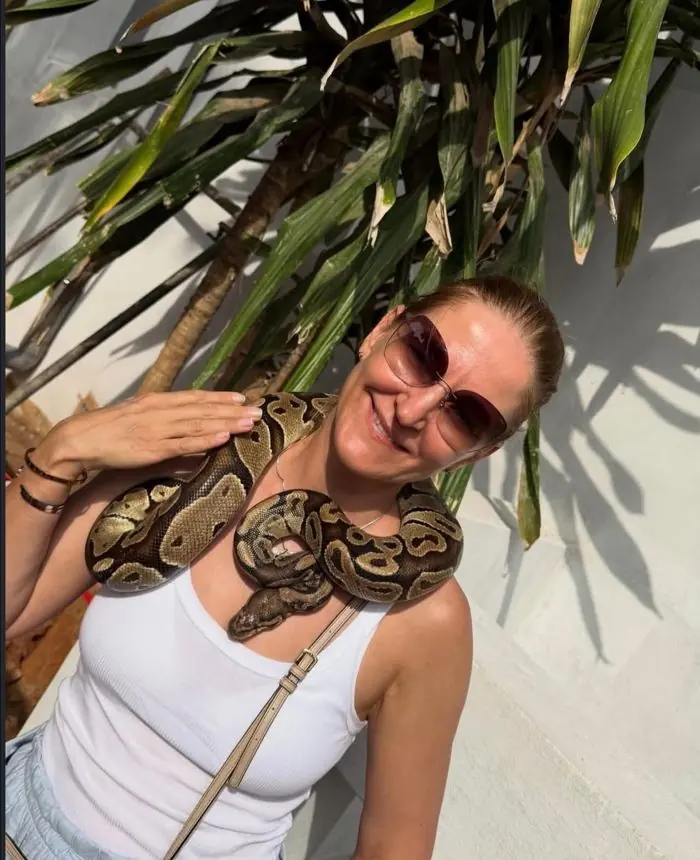 Visiteuse souriante avec un python royal autour du cou à Ouidah.
